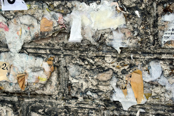 A brick wall covered with scraps of paper and ads