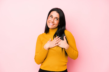 Young caucasian woman isolated on a pink background has friendly expression, pressing palm to chest. Love concept.