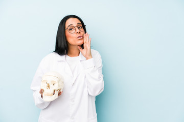 Doctor caucasian woman isolated on blue background is saying a secret hot braking news and looking...