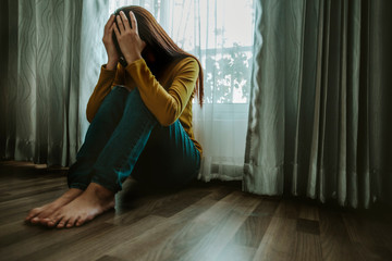 Sad young woman sitting on the bed in the bedroom, People with depression concept.	