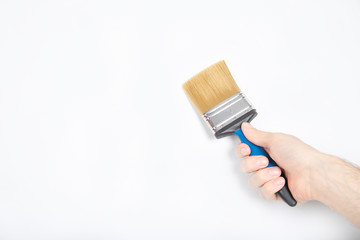 The guy holds a brush in his hand. White wall, repair. builder