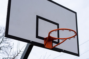 Basketball backboard and ring on sky background.