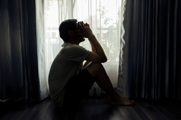 Sad young man sitting on the bed in the bedroom, People with depression concept.