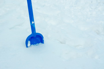 Children's blue shovel stuck in the snow.
