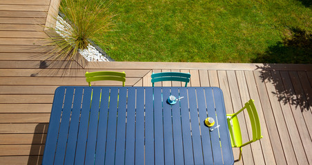 Table et salon de jardin moderne sur une terrasse en bois.