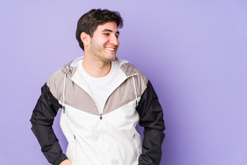 Fototapeta premium Young man isolated on purple background laughs happily and has fun keeping hands on stomach.