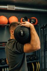 Muscular athletic man exercise with medicine ball at health club or gym. Fitness routine with exercise ball to maintain the abs. Sport, exercising, training and lifestyle concept.