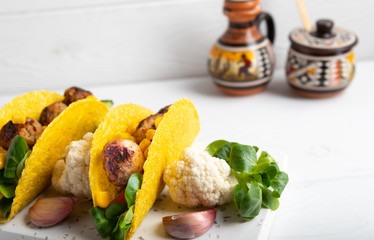 Taco with vegan meatballs and vegetables, on a white background.