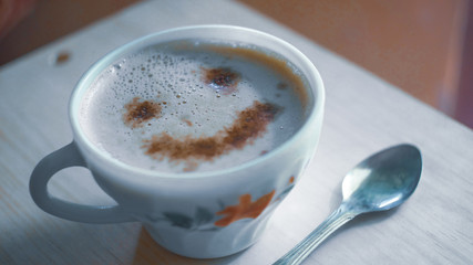 cup of coffee with cream on wooden background