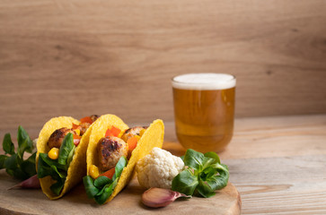 Taco with vegan meatballs and vegetables, on a wooden table as background.