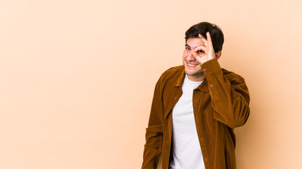 Fototapeta premium Young man isolated on beige background excited keeping ok gesture on eye.