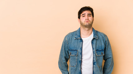 Young man isolated on beige background sad, serious face, feeling miserable and displeased.