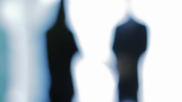 A pair of unidentifiable human silhouettes in business attire shaking hands with defocused effect.