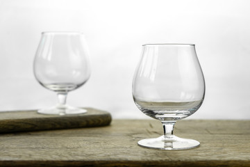 Cognac \ whiskey in cognac glass on wooden table, golden color spirits splashing on white background