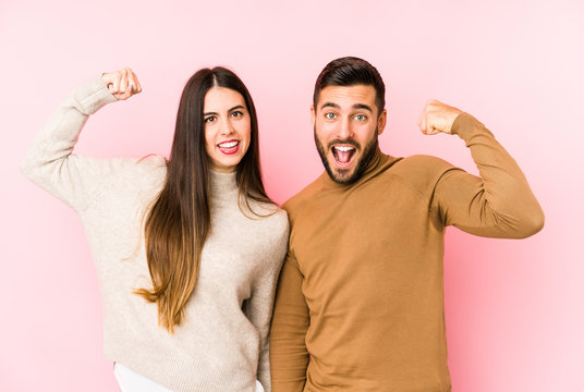 Young Caucasian Couple Isolated Showing Strength Gesture With Arms, Symbol Of Feminine Power