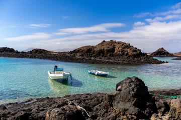 Dos barcas flotando sobre el mar azulado de una isla.