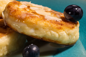 Cheese pancake with almonds and blueberries poured with condensed milk on a blue plate