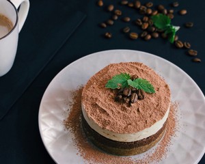  Tiramisu on a black plate. Coffee with cinnamon. Raw dessert