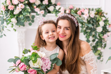 mother with a cute daughter in elegant dresses on the background of a beautiful interior with...