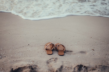 Fototapeta na wymiar Women's sandals in the beach sand