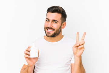 Young caucasian man holding a vitamins bottle isolated showing number two with fingers.