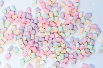 Fototapeta na wymiar Top View of Pastel Shaped Marshmallow Candies with Some Scattered on the Pale white Table