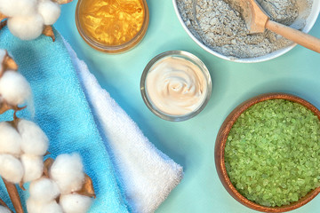 spa massage clay powder, face masks, bath salt, towel, shea butter on blue table background.
