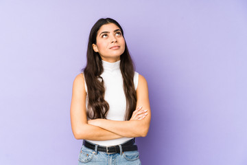 Young indian woman isolated on purple background tired of a repetitive task.