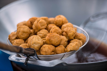 Hand of chef holding frying pan cooking fry the fish balls on a pan in kitchen stove, fried food concept.