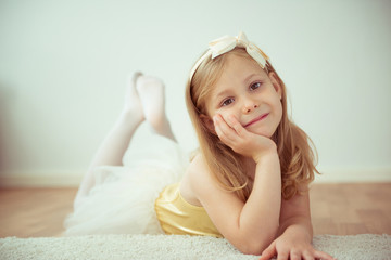 Cute little blonde girl sitting in ballet tutu