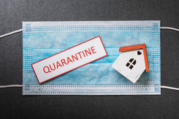 Medical mask, sheet with the inscription and a toy house, top view. Concept on the topic of quarantine - obrazy, fototapety, plakaty