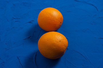 Two juicy ripe orange on a textural blue background. Flat lay, top view. Pop art design, creative summer concept. Citrus fruits in a minimalist style. Copy space