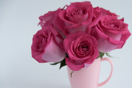 Bouquet of pink roses on a light background. A bouquet of flowers stands in a pink mug. Pink vase.