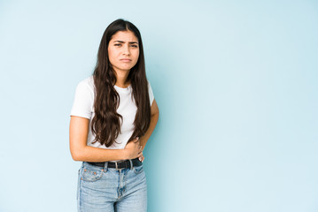 Young indian woman on blue background having a liver pain, stomach ache.