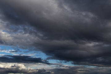 Naklejka na ściany i meble Dramatic storm dark grey cumulus clouds against blue sky background texture