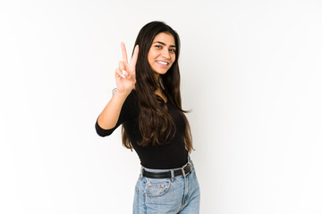 Young indian woman isolated on purple background joyful and carefree showing a peace symbol with fingers.