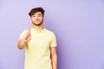 Young arabian man isolated on a purple background showing number one with finger.