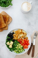 Fresh omelette for breakfast with mixed vegetables: rocket, tomatoes, cucumber, olives, cheese. Top view. Copy space.