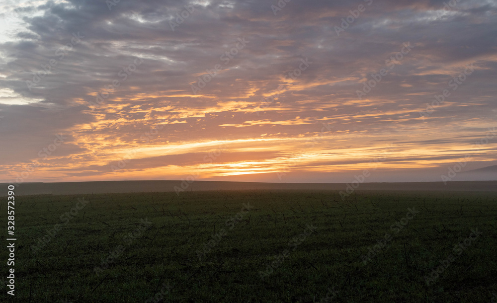 Wall mural Countryside sunset landscape with agricultural fields. Beautiful orange clouds