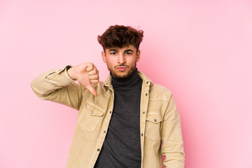 Young arabian man posing in a background isolated showing a dislike gesture, thumbs down....