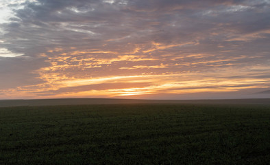Countryside sunset landscape with agricultural fields. Beautiful orange clouds