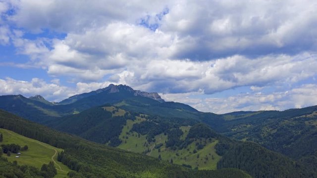 Time lapse video of summer mountain, aerial video of forest and rocky mountain with moving clouds in Romanian Carpathians