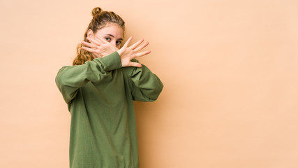 Young caucasian woman isolated on beige background keeping two arms crossed, denial concept.