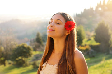 Relaxed young woman breathing fresh air with a green natural landscape on the background