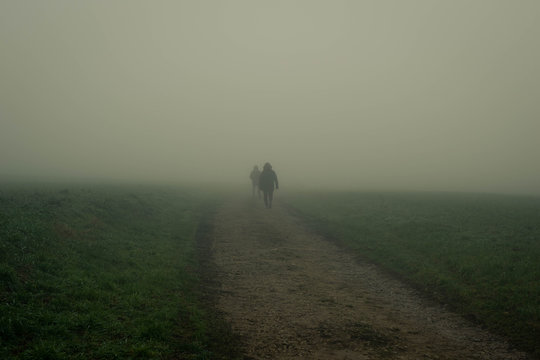 Two people walking down a path with mist. Mysterious and adventurous photo.