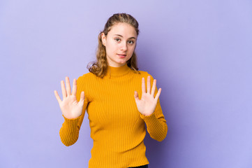 Young caucasian woman on purple background rejecting someone showing a gesture of disgust.