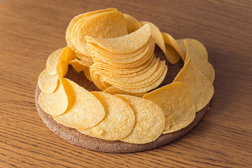 Delicious potato chips, laying on wooden table background