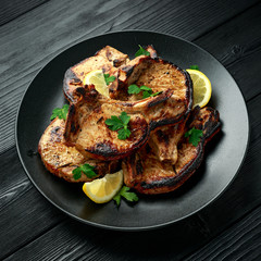 Homemade Grilled Pork loin chops in lemon sauce with herbs on rustic wooden table