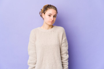 Young caucasian woman on purple background shrugs shoulders and open eyes confused.