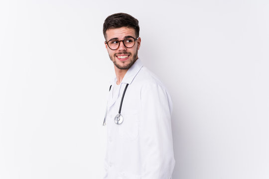 Young caucasian doctor man isolated looks aside smiling, cheerful and pleasant.